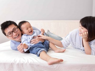 happy family playing on white bed in the bedroom at home, asian people